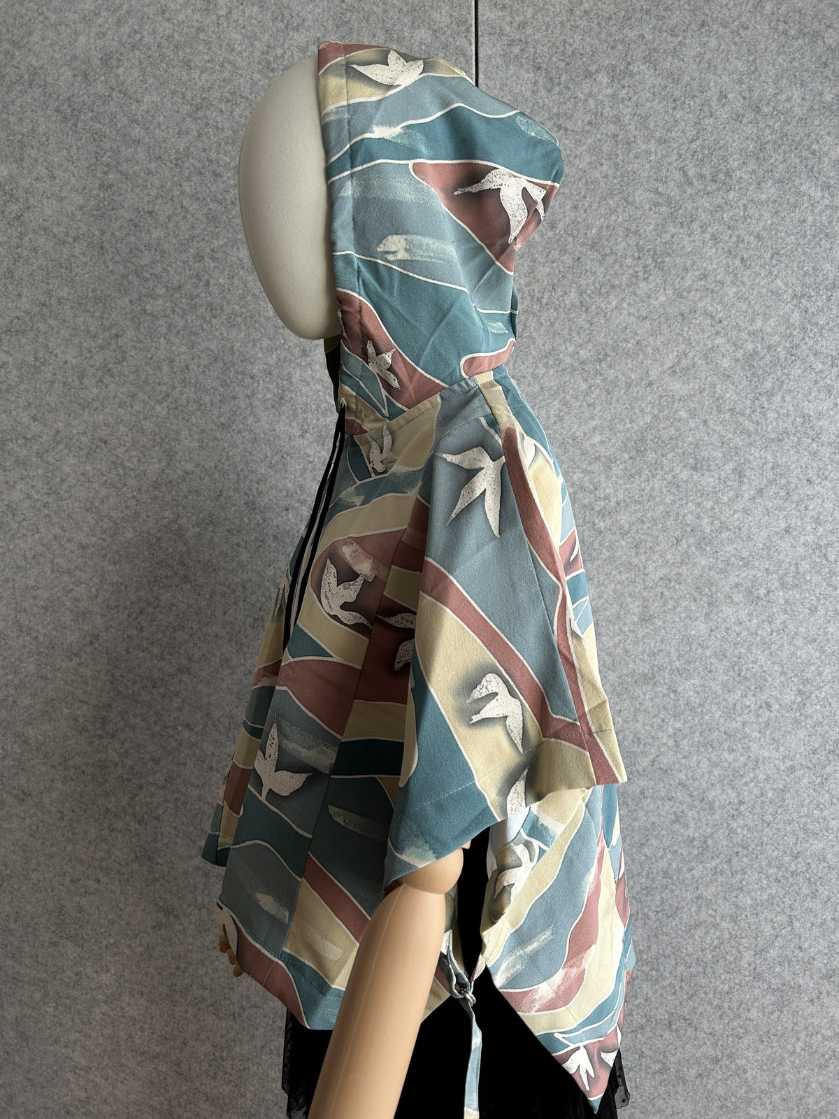 Teal blue hooded kimono poncho with yellow and red waves, side view
