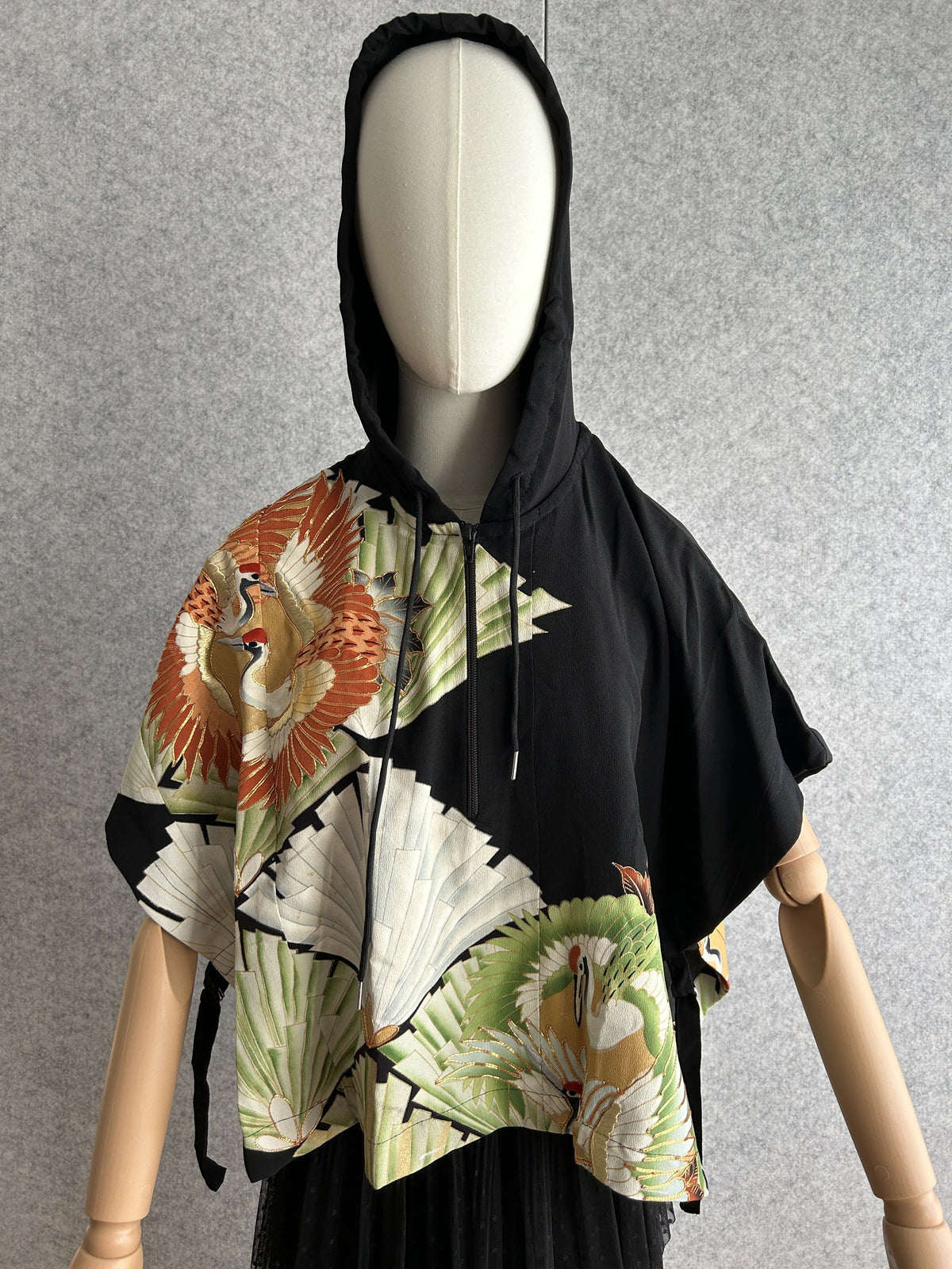 Black hooded kimono poncho with orange cranes and green fans, front view