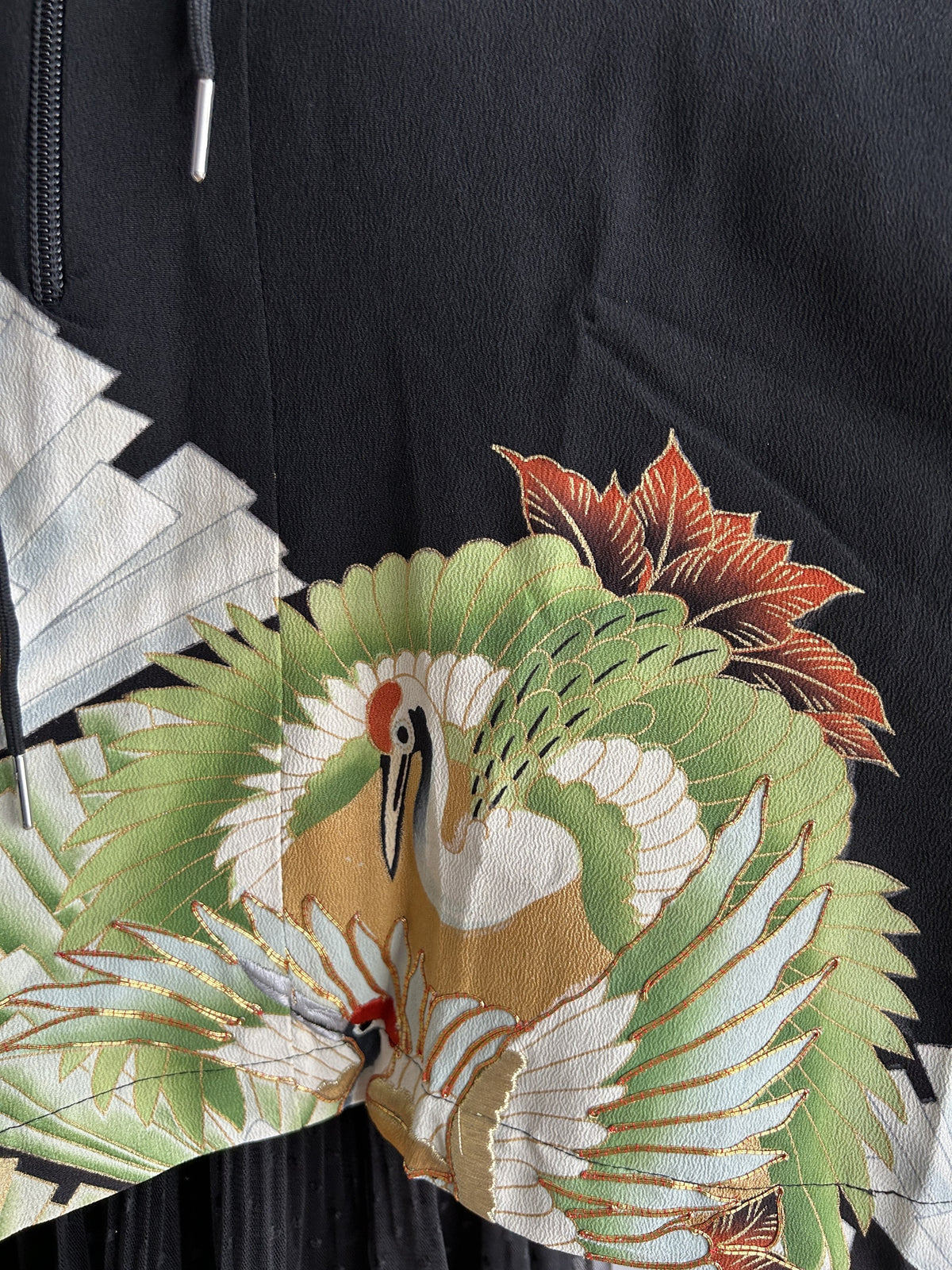 Black hooded kimono poncho, detail of green crane near the hem