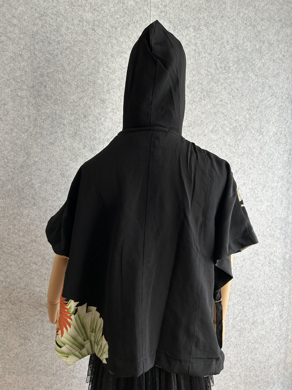 Black hooded kimono poncho with small patterned corner, back view