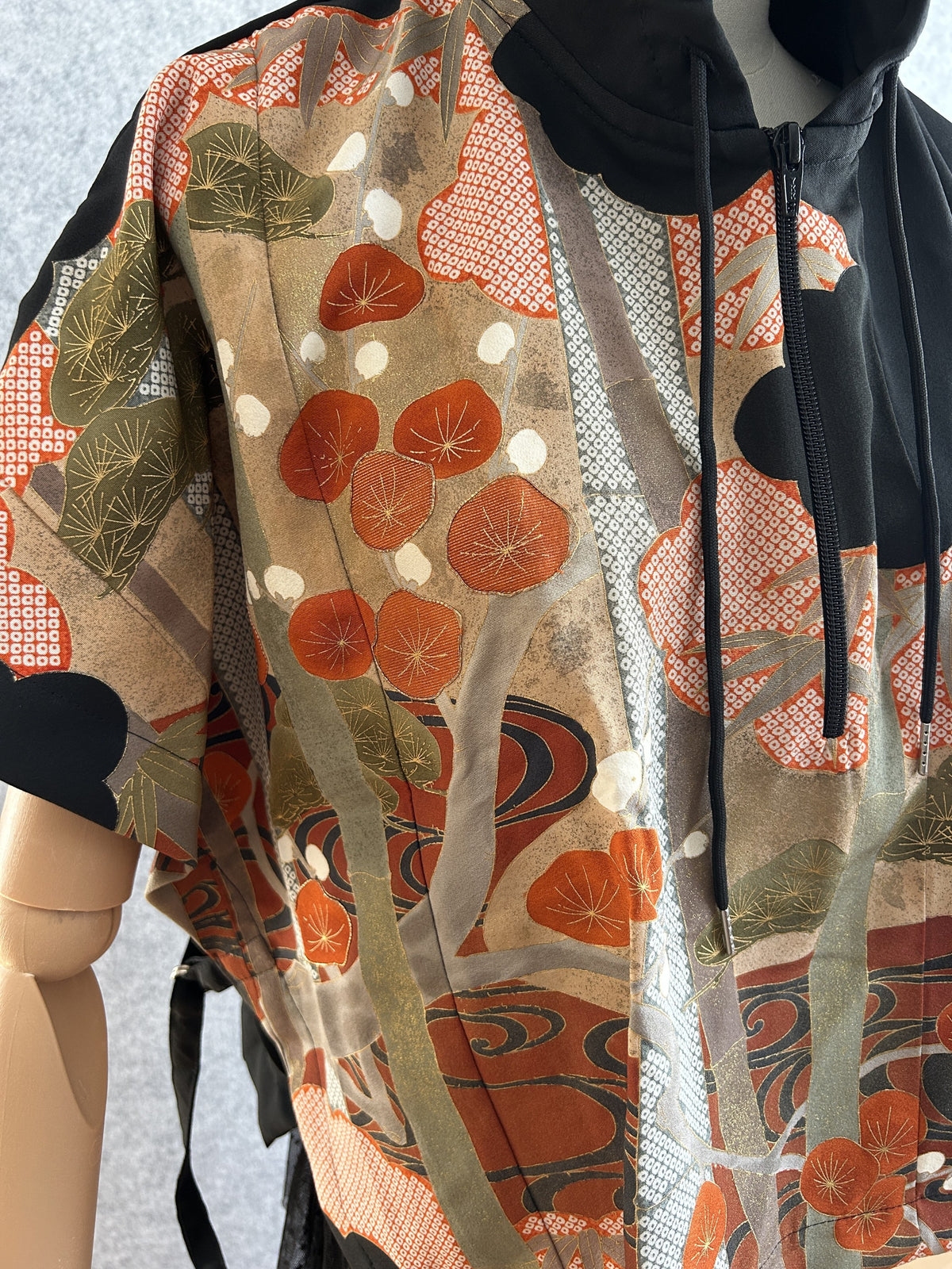 Black hooded kimono poncho, close-up of red blossom and pine pattern at front zipper