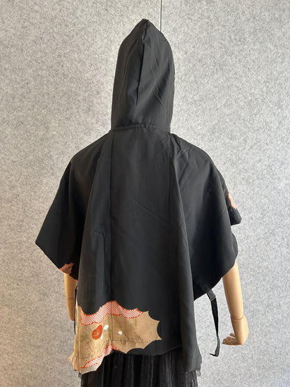 Black hooded kimono poncho with small patterned corner at the hem, back view