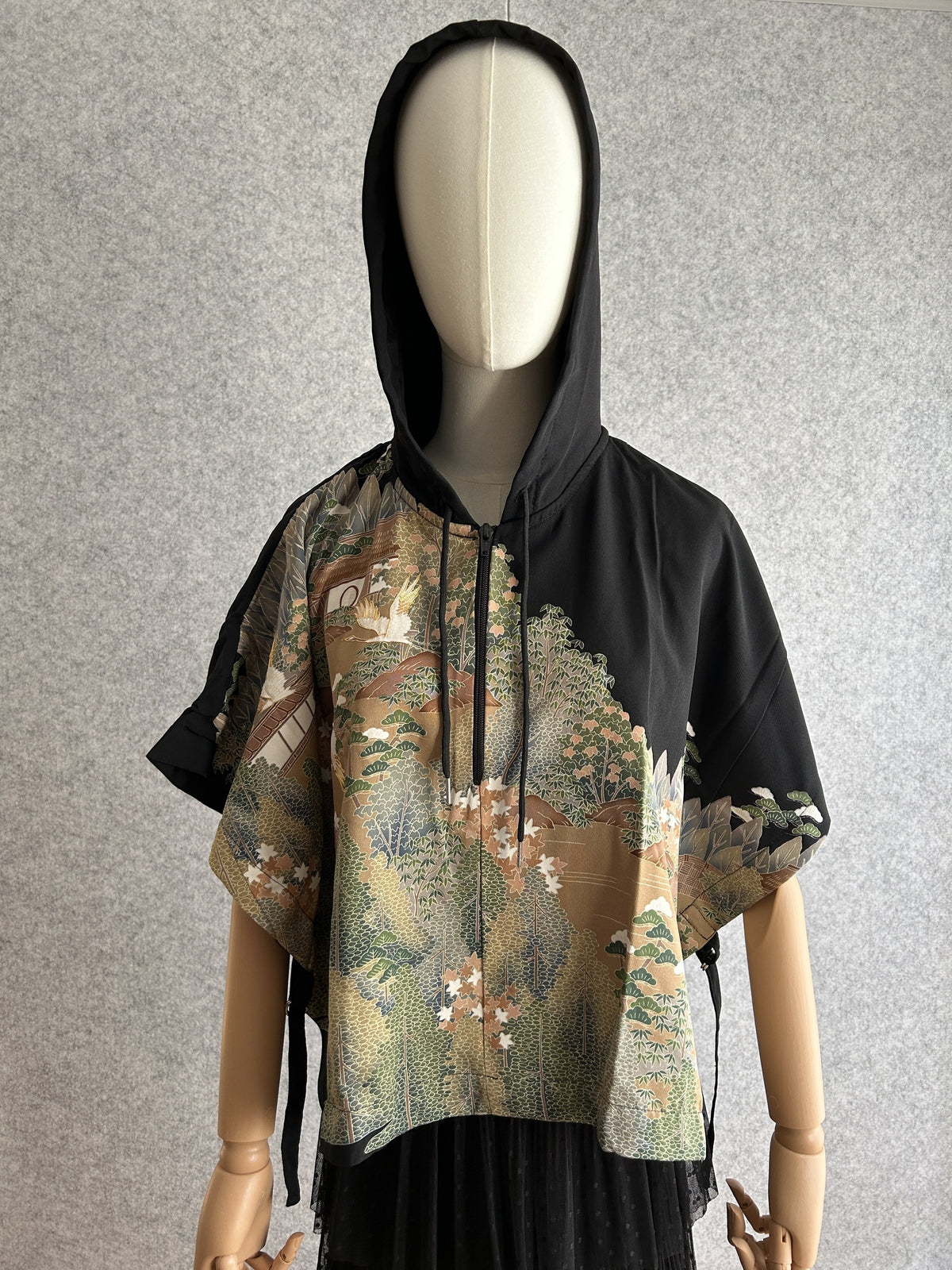 Black hooded kimono poncho with green and beige landscape scene, front view