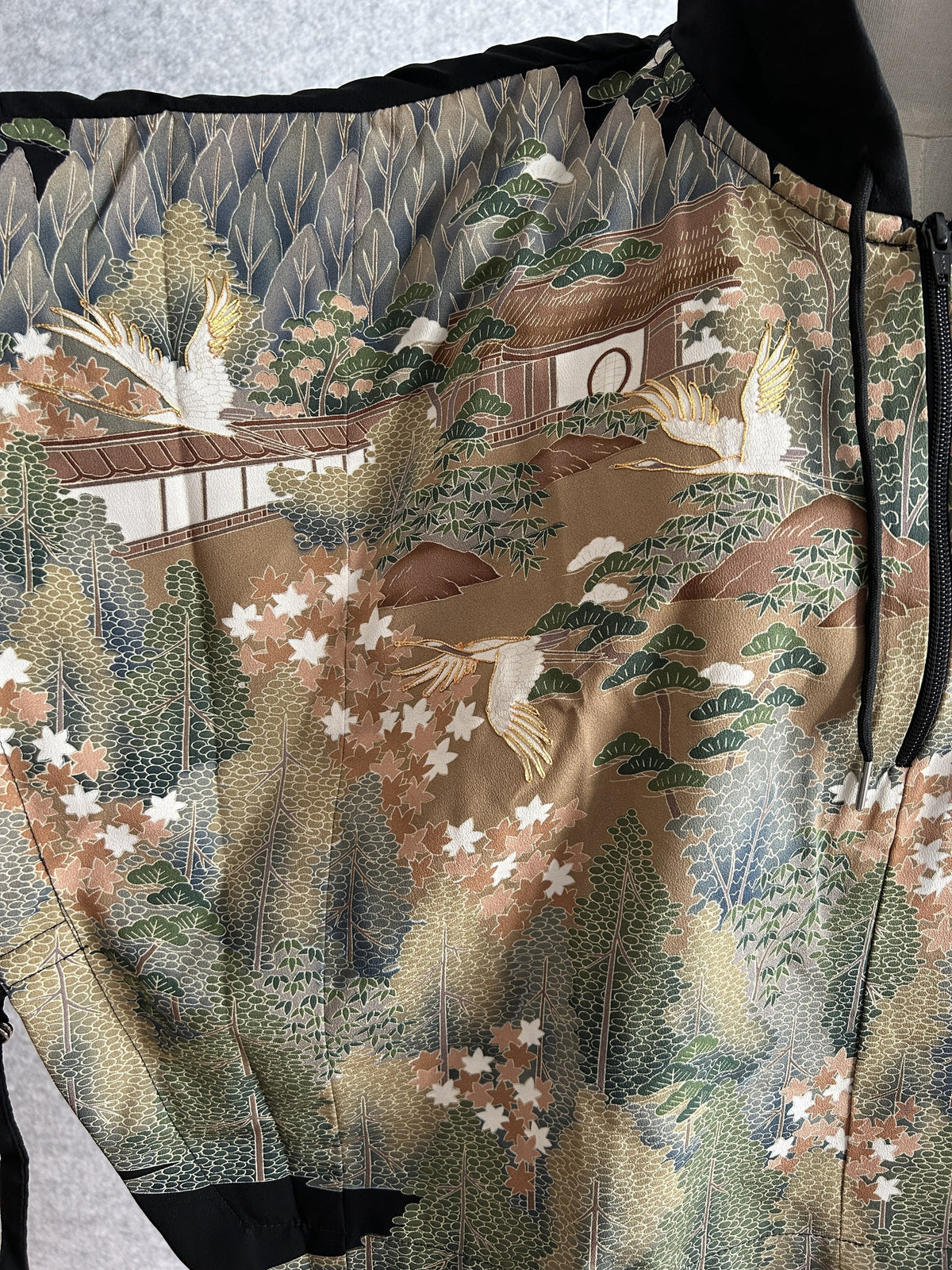 Black hooded kimono poncho, close-up of building, trees and flying cranes pattern