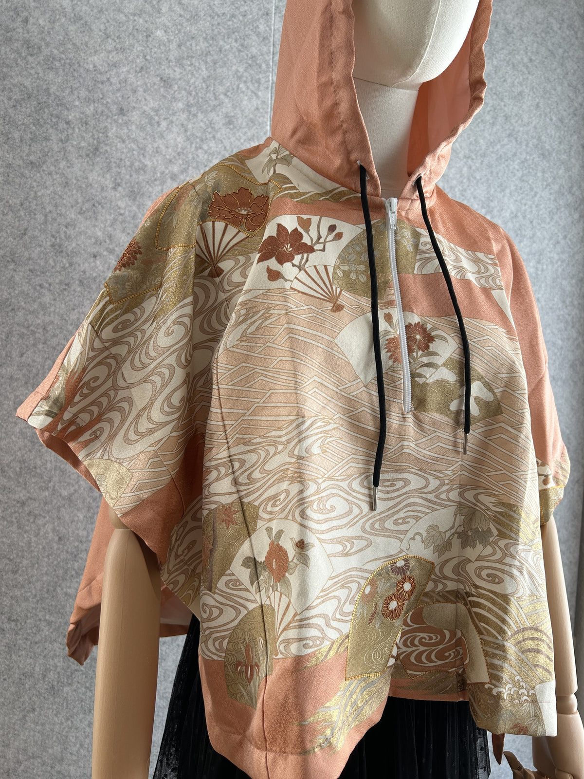Salmon pink hooded kimono poncho with fan and wave pattern, angled front view