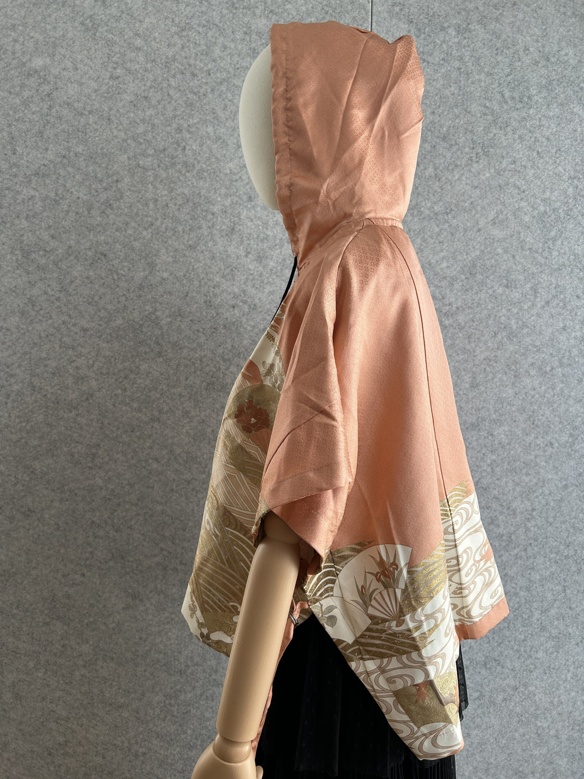 Salmon pink hooded kimono poncho with fan pattern at the hem, side view