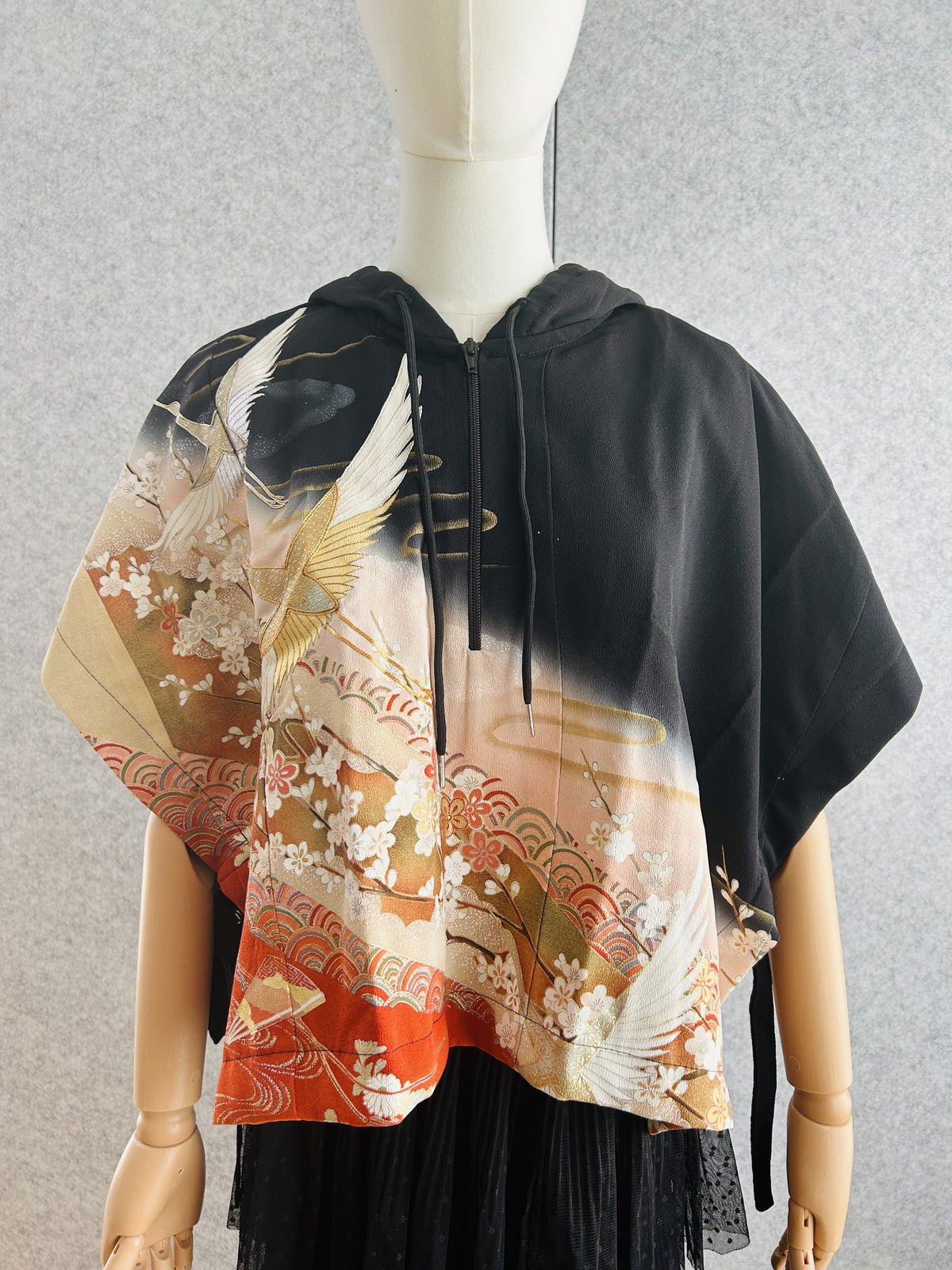 Black hooded kimono poncho with cranes and plum blossoms in peach and orange, front view