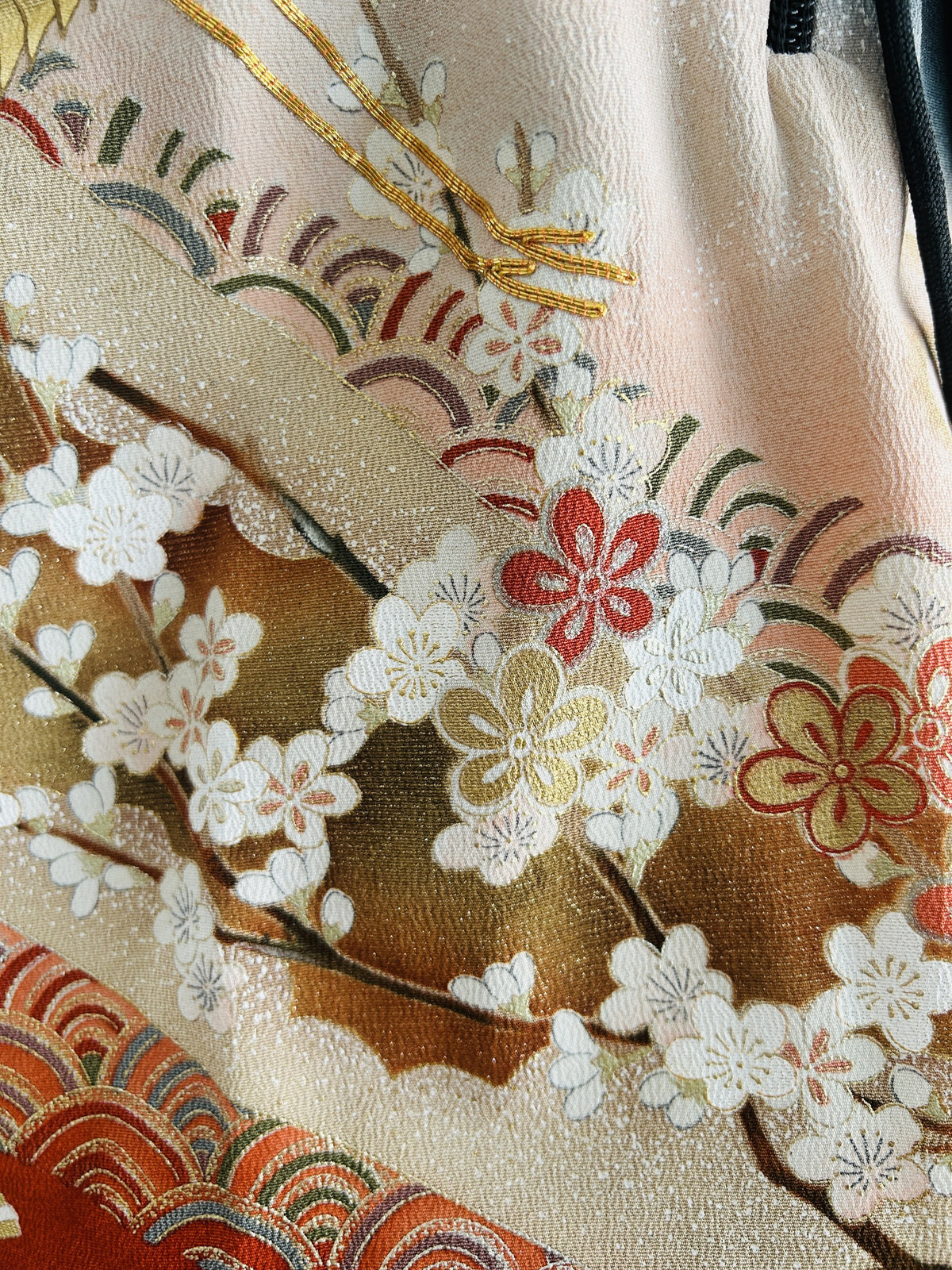 Detail of white and red plum blossoms and wave bands with gold accents