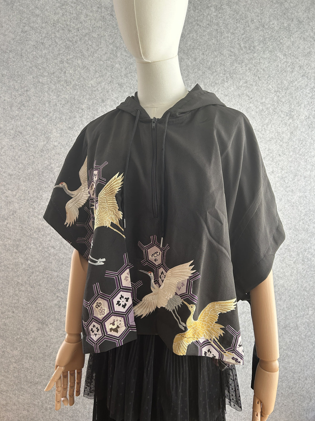 Black hooded kimono poncho with white and gold cranes and lilac hexagons, front view