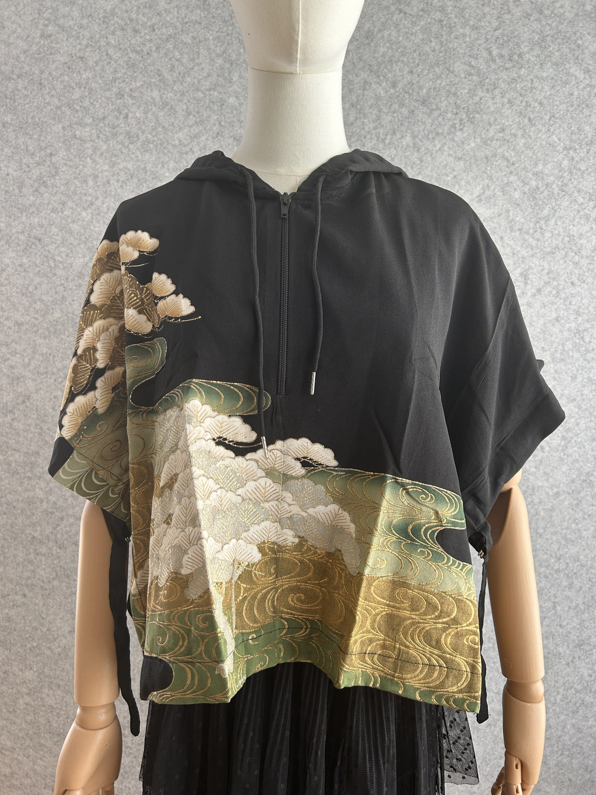 Black hooded kimono poncho with white pines and green gold water swirls, front view
