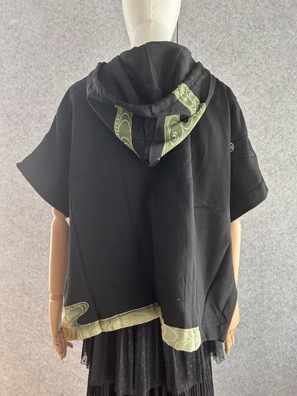 Black hooded kimono poncho with green swirl hood panel and hem, back view