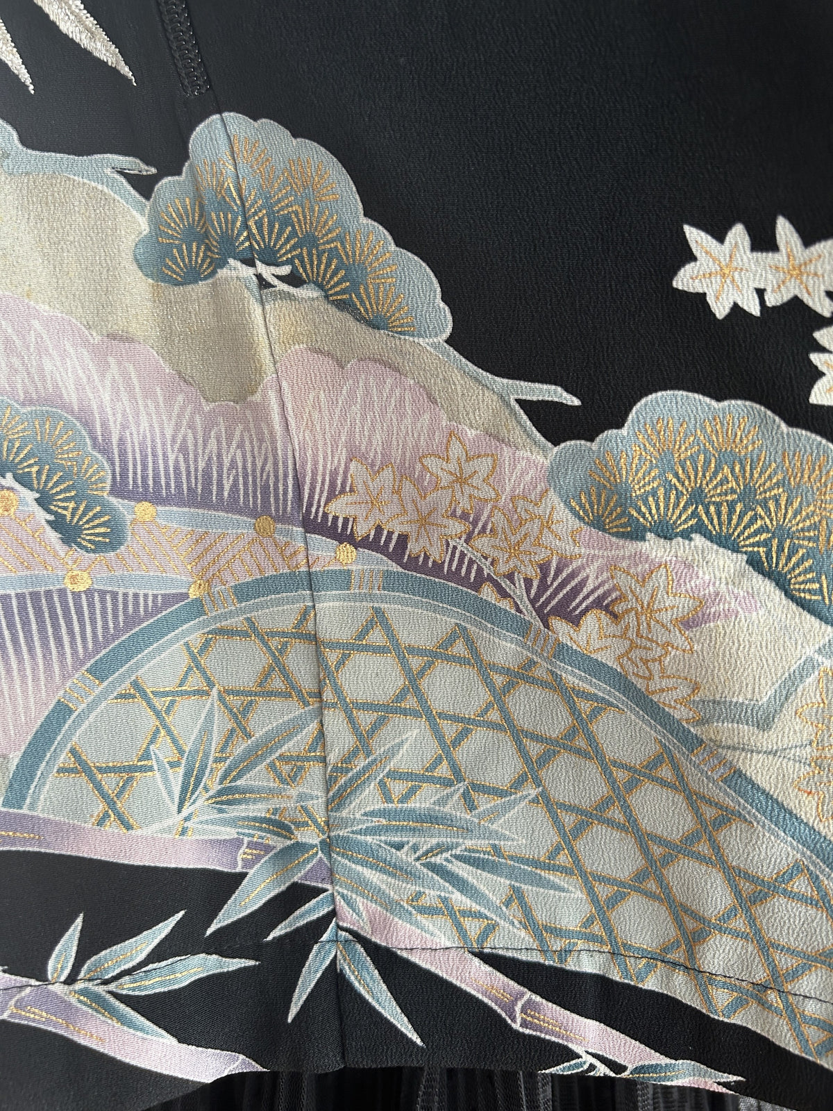 Close-up of pale blue pines, bamboo and lattice fence on black fabric
