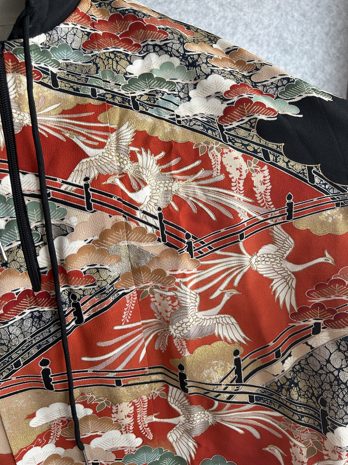 Black hooded kimono poncho, close-up of white birds, fence and pine trees on red