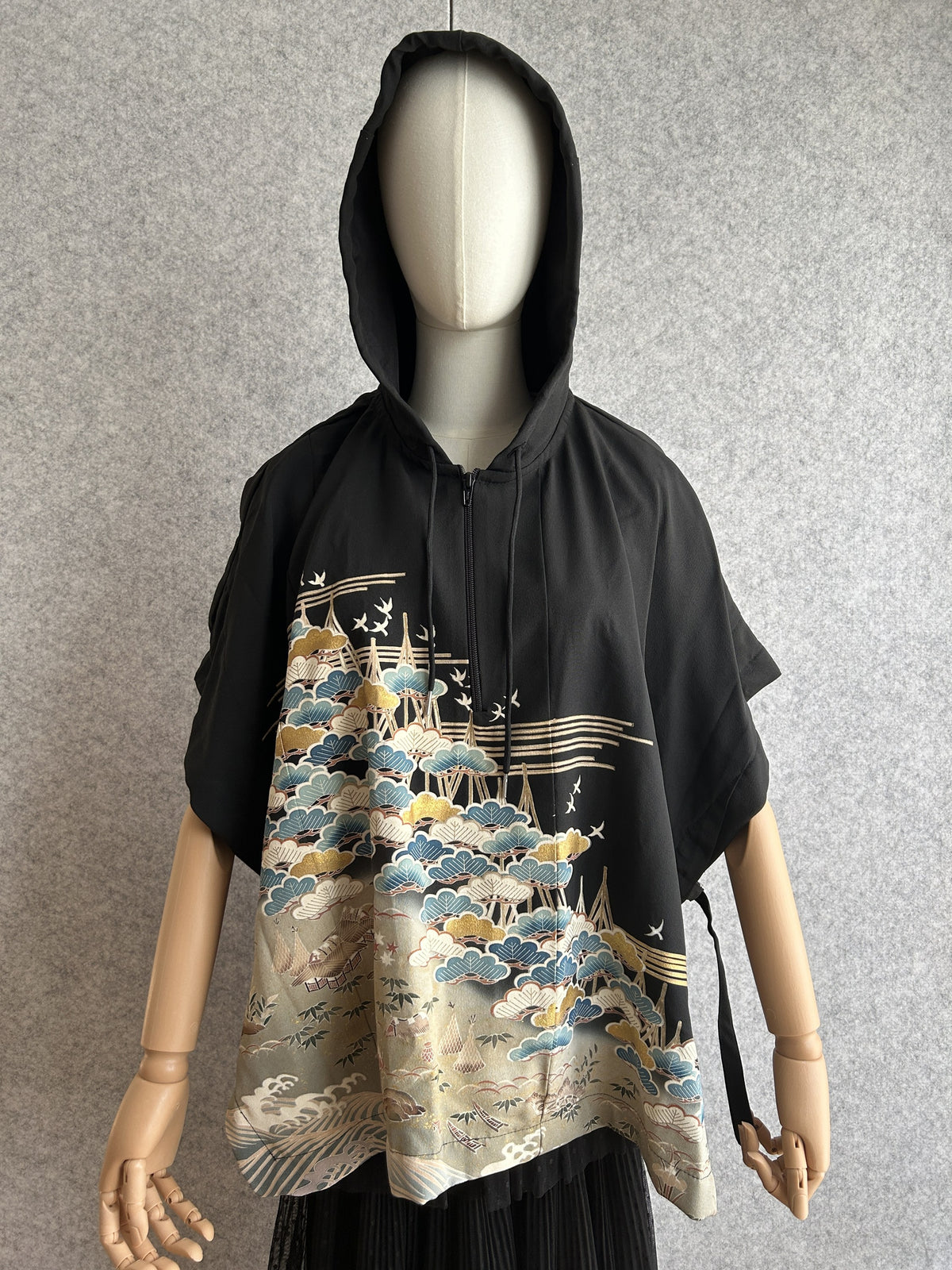 Black hooded kimono poncho with blue and gold pine tree scene, front view
