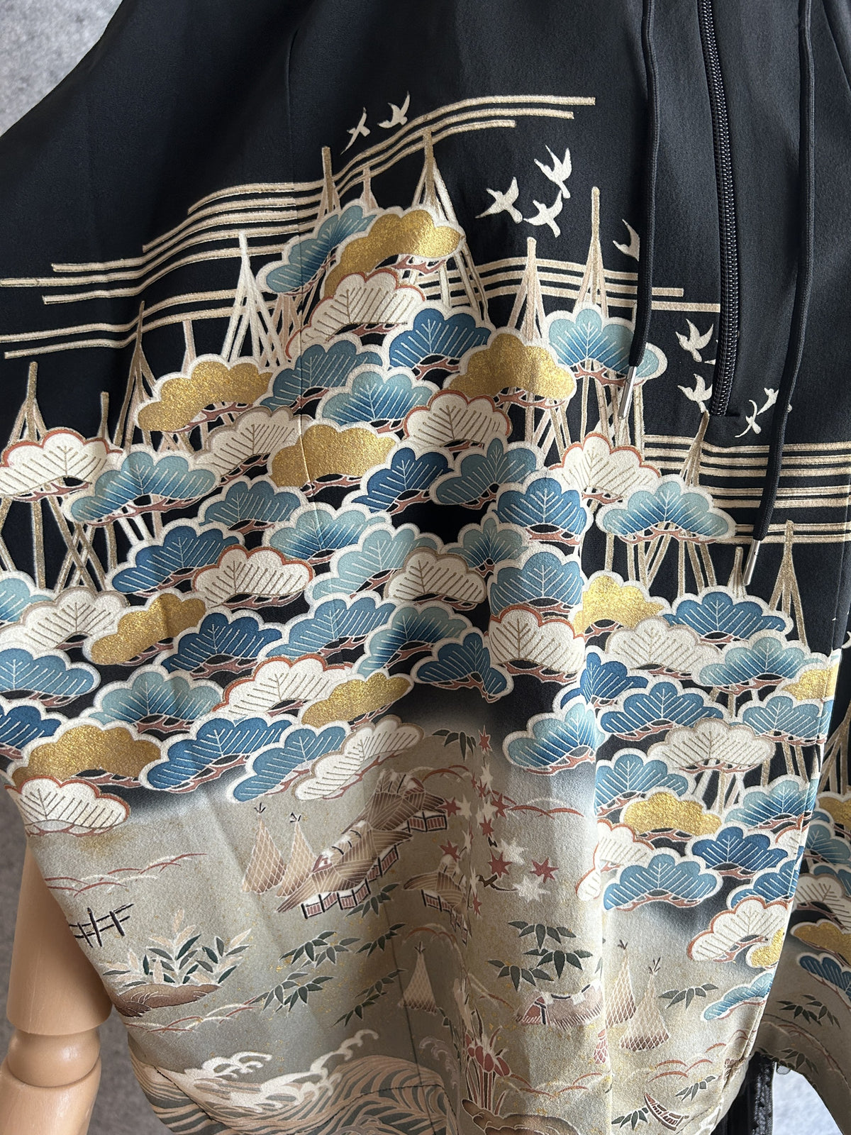 Black hooded kimono poncho, close-up of blue, white and gold pine trees and birds