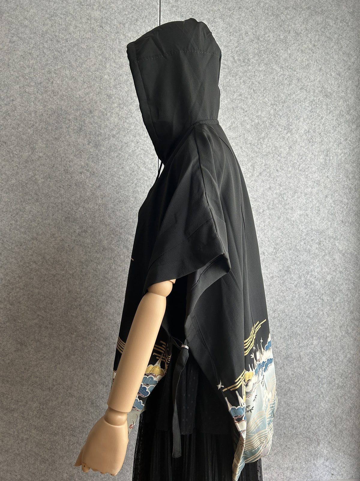 Black hooded kimono poncho with patterned hem, side view