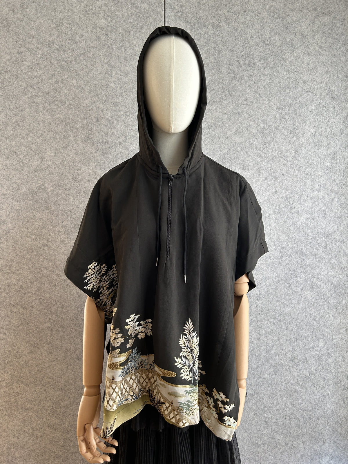 Black hooded kimono poncho with white and gold tree scene at hem, front view