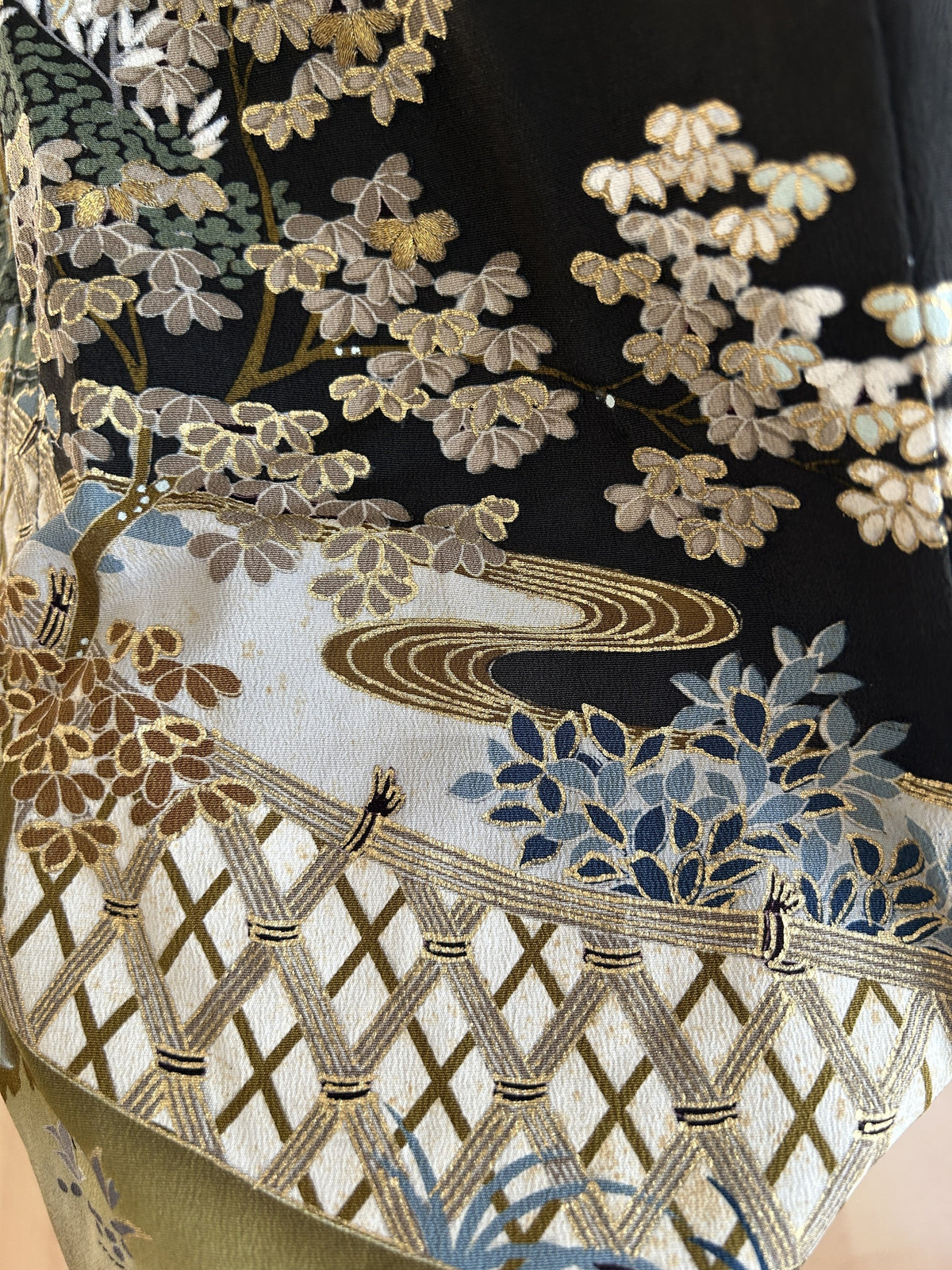 Black hooded kimono poncho, detail of gold-outlined leaves and white lattice fence