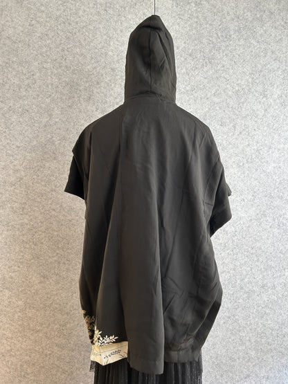 Black hooded kimono poncho with small patterned corner at the hem, back view