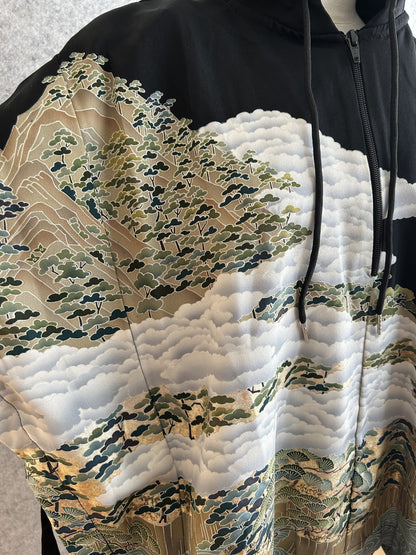 Black hooded kimono poncho, close-up of clouds and pine-covered hills at the zipper