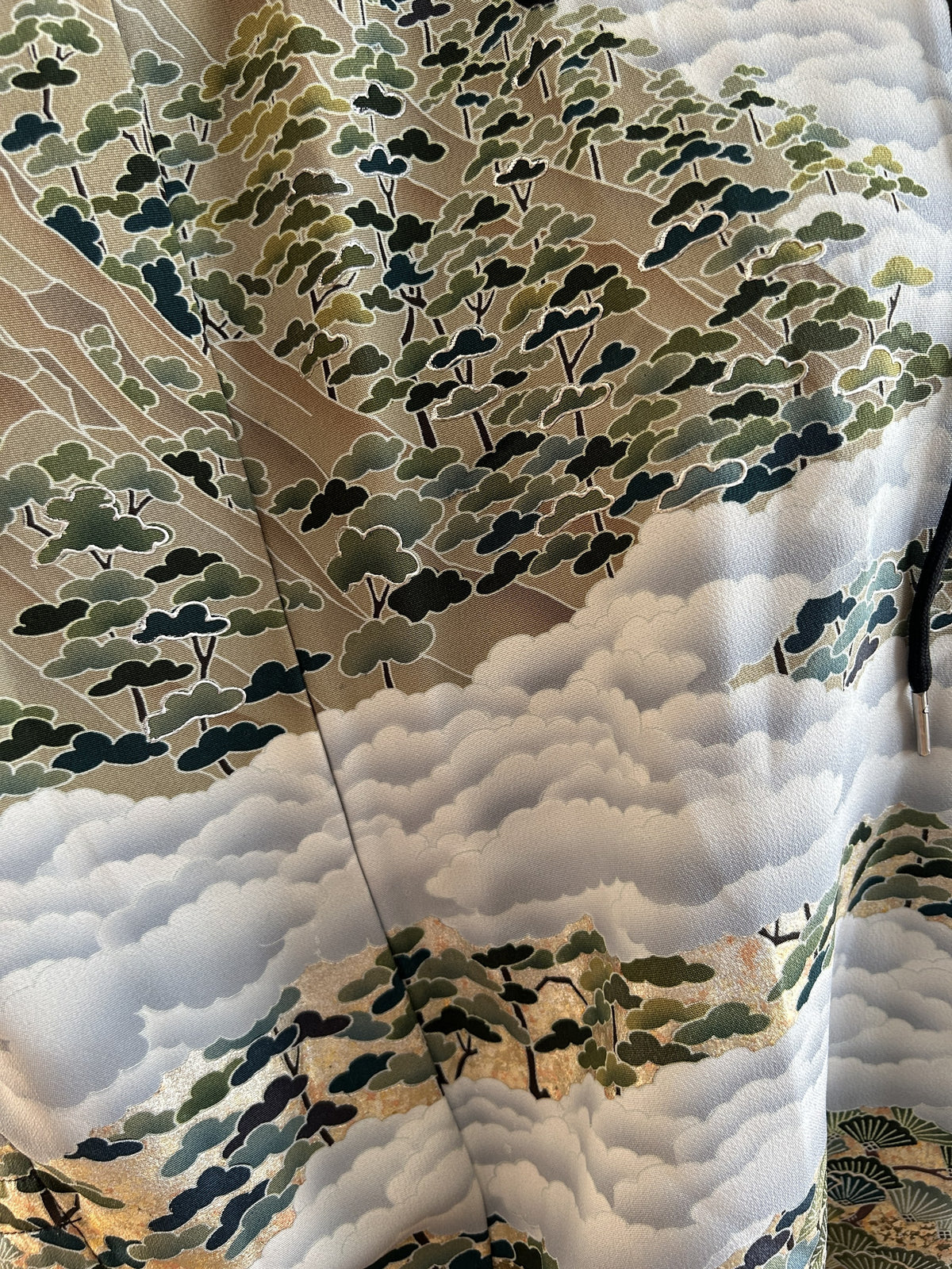 Black hooded kimono poncho, detail of white clouds and green pine trees