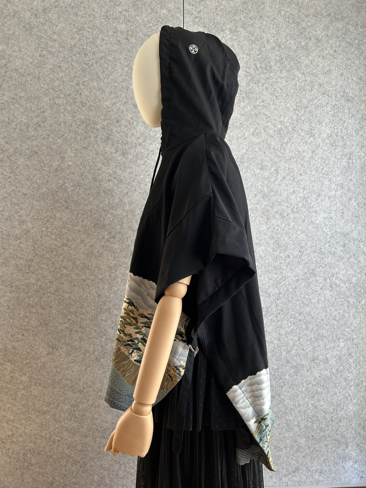 Black hooded kimono poncho with cloud pattern at the hem, side view