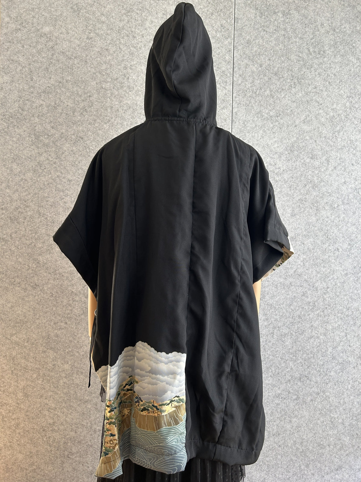 Black hooded kimono poncho with cloud and pine panel at the hem, back view