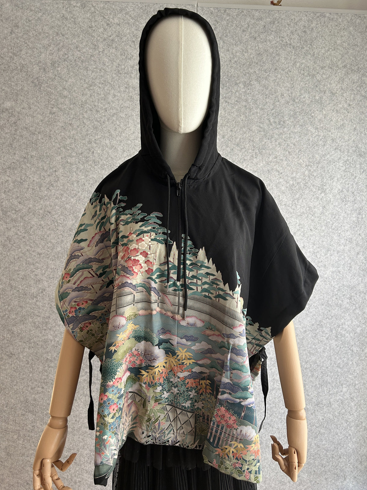 Black hooded kimono poncho with pastel garden scene in teal and pink, front view