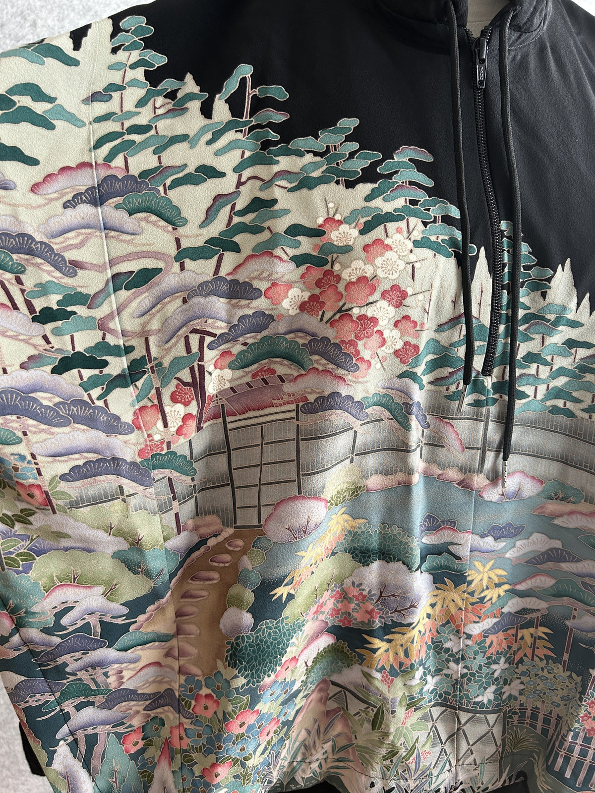 Black hooded kimono poncho, close-up of pine trees, blossoms and garden gate