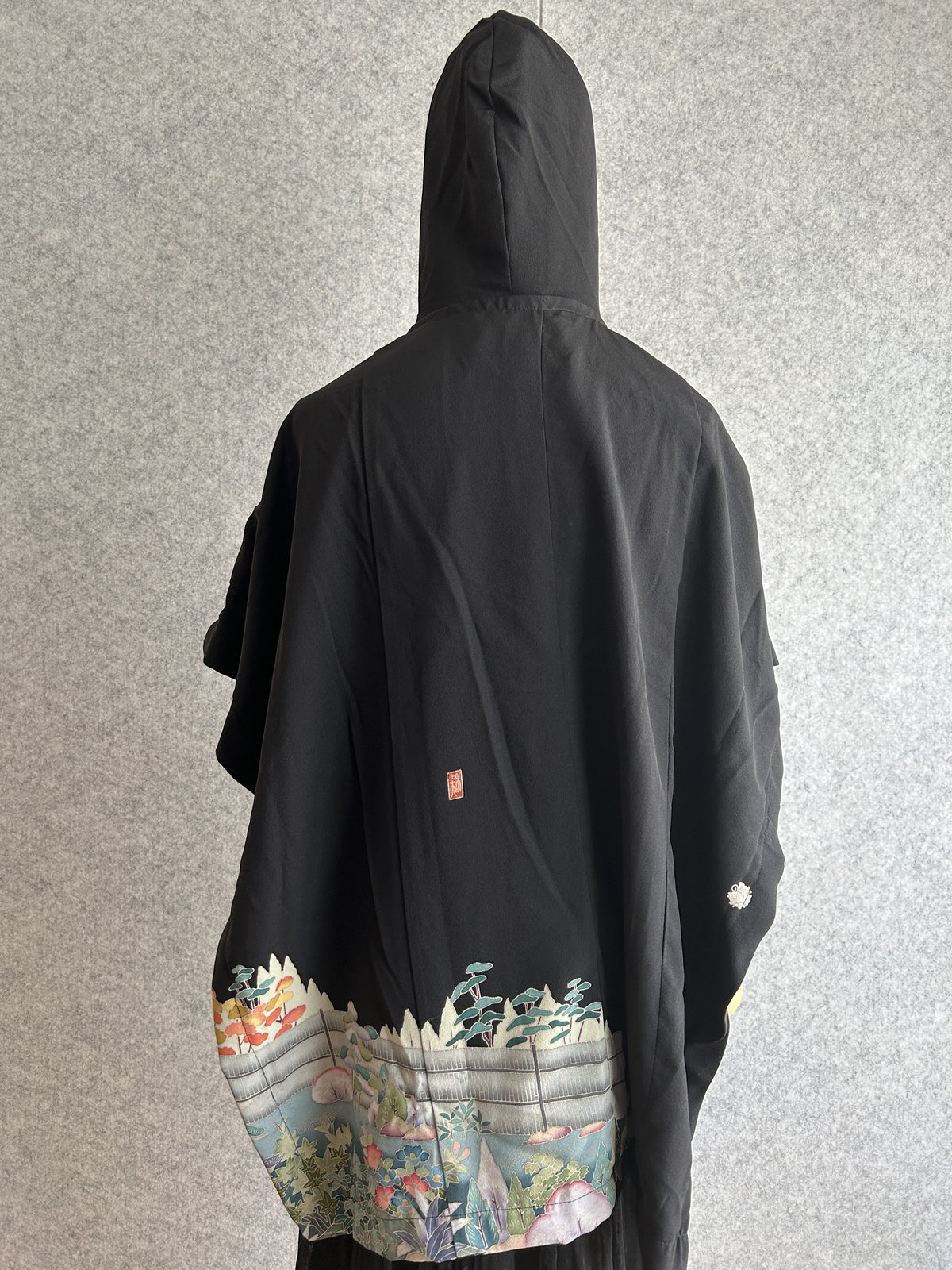 Black hooded kimono poncho with garden scene at the hem, back view
