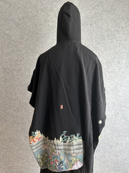 Black hooded kimono poncho with garden scene at the hem, back view