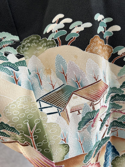 Black hooded kimono poncho, detail of thatched houses among trees and hills