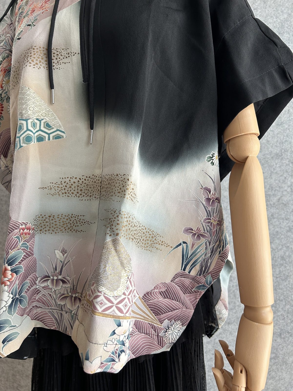 Black hooded kimono poncho, detail of lower front with fading black and flowers