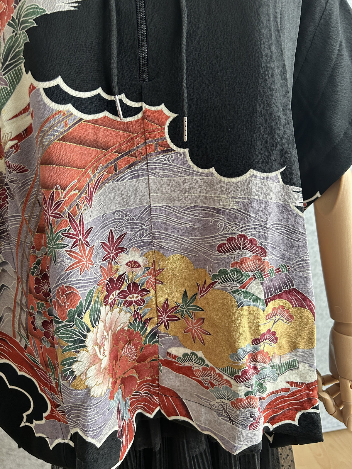 Black hooded kimono poncho, detail of lower front with maple leaves and flowers