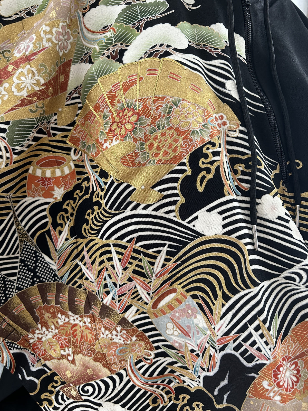 Black hooded kimono poncho, close-up of gold folding fans, waves and zipper