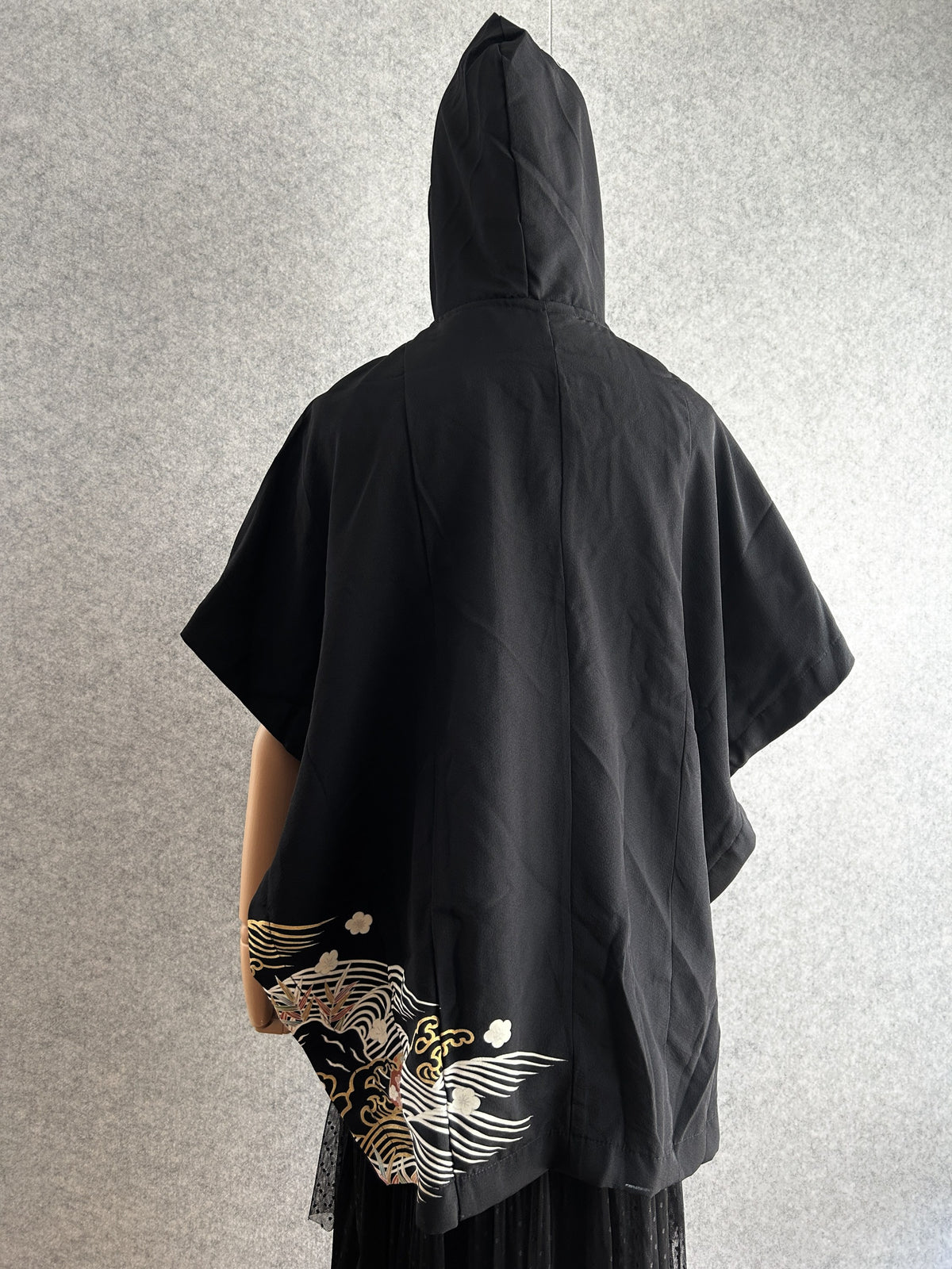 Black hooded kimono poncho, back view with small wave design at hem