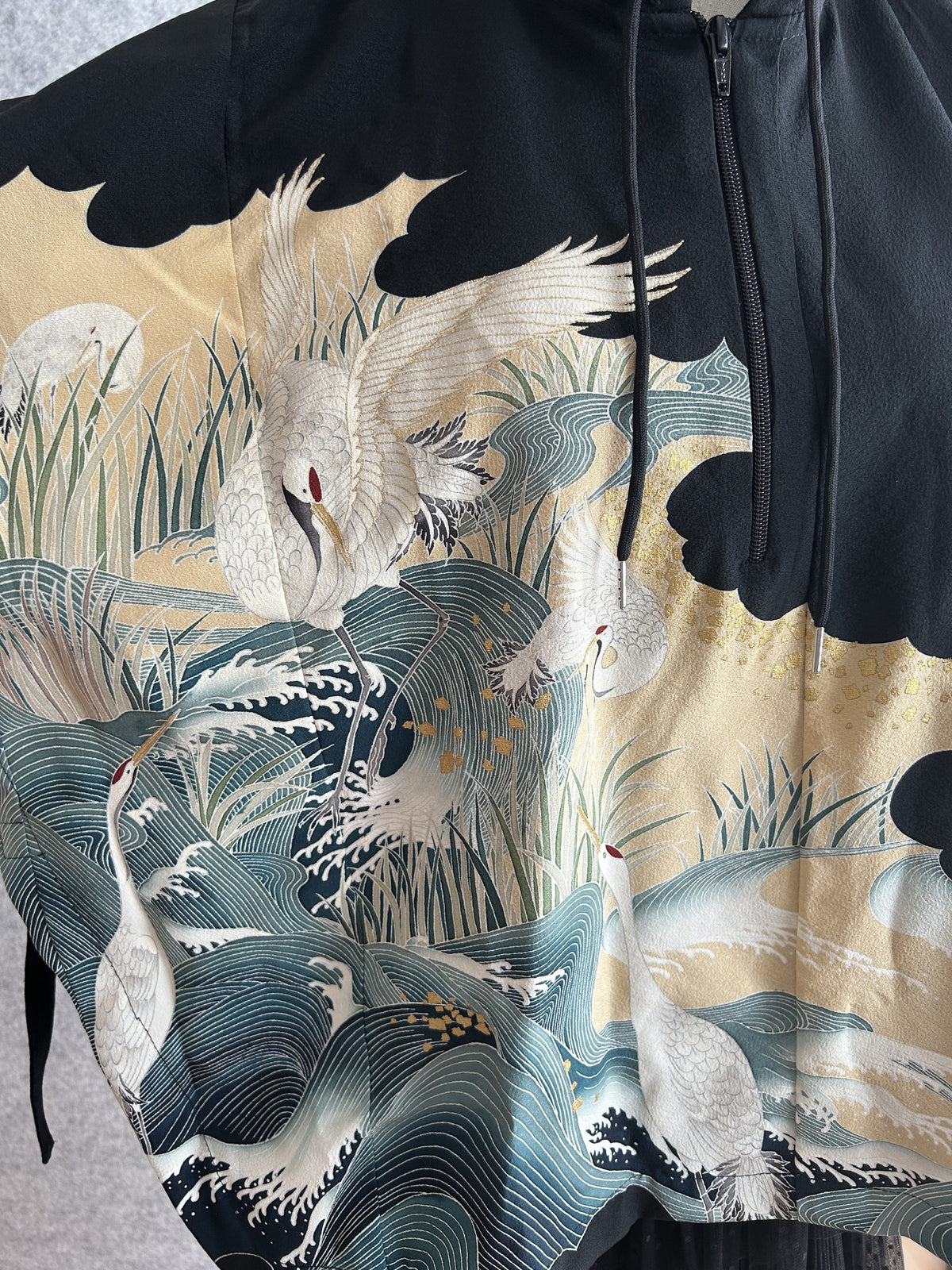Black hooded kimono poncho, close-up of white cranes, reeds and waves