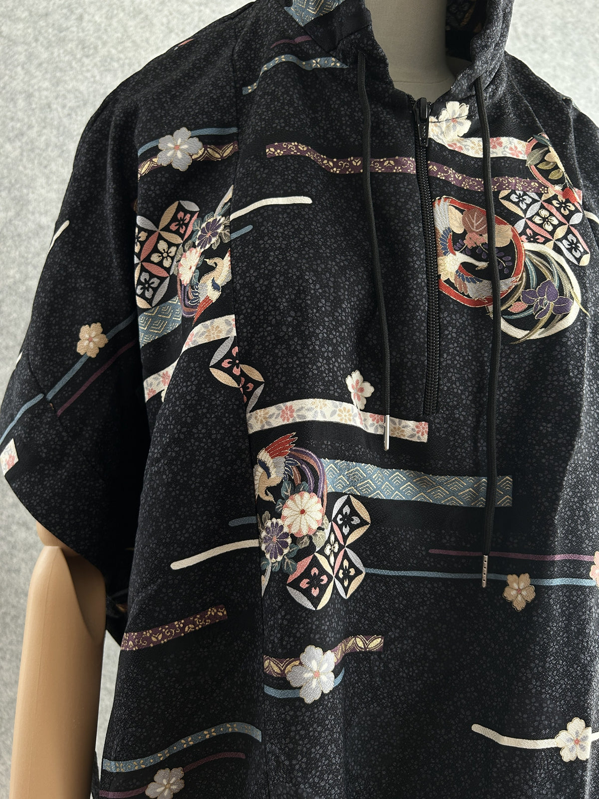 Black hooded kimono poncho, detail of zipper, drawstring and ribbon pattern