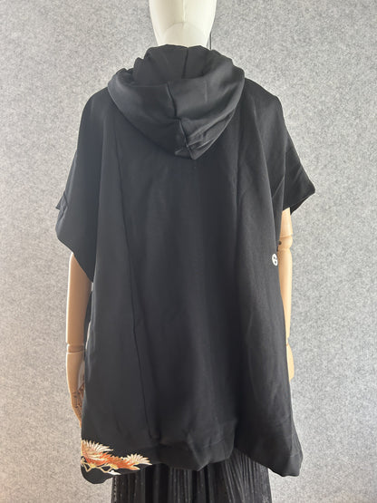 Black hooded kimono poncho with small orange motif at hem, back view