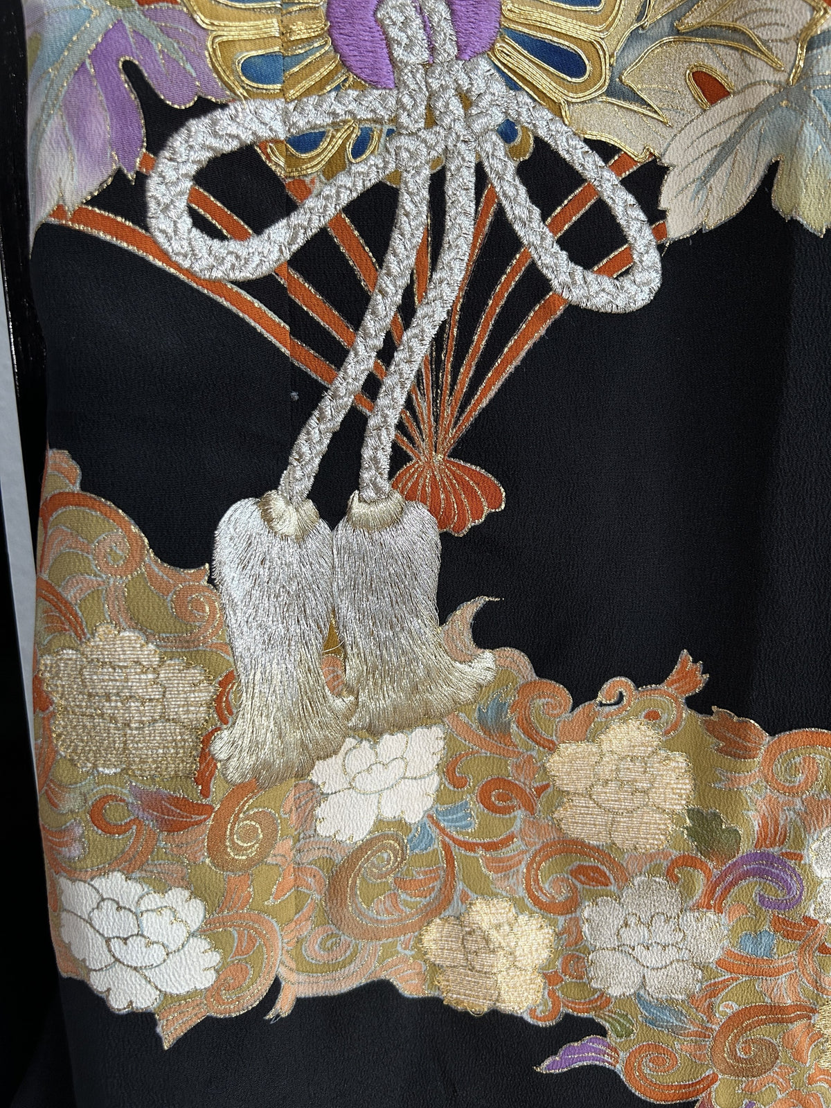 Silver cord with tassels above floral band on black kimono skirt