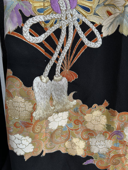 Silver cord with tassels above floral band on black kimono skirt
