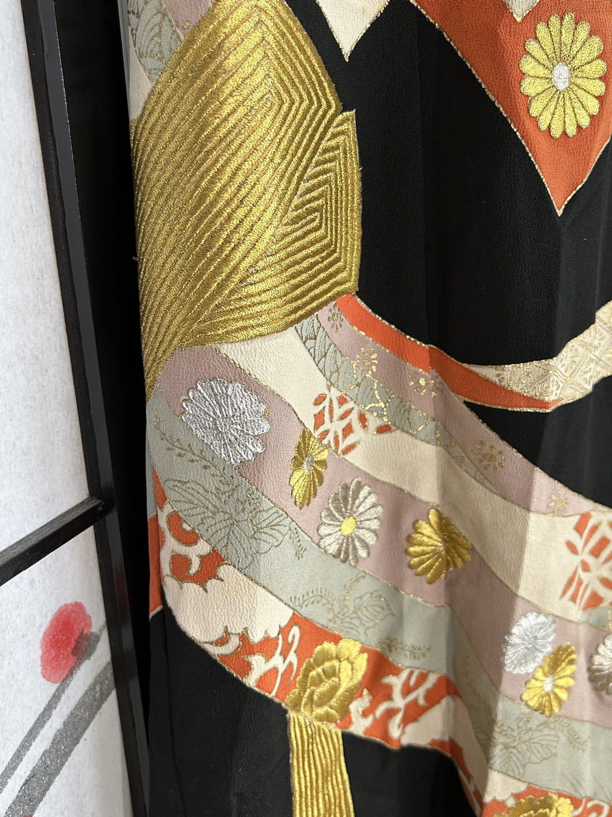 Gold textured band and coloured ribbons on black kimono skirt, close-up
