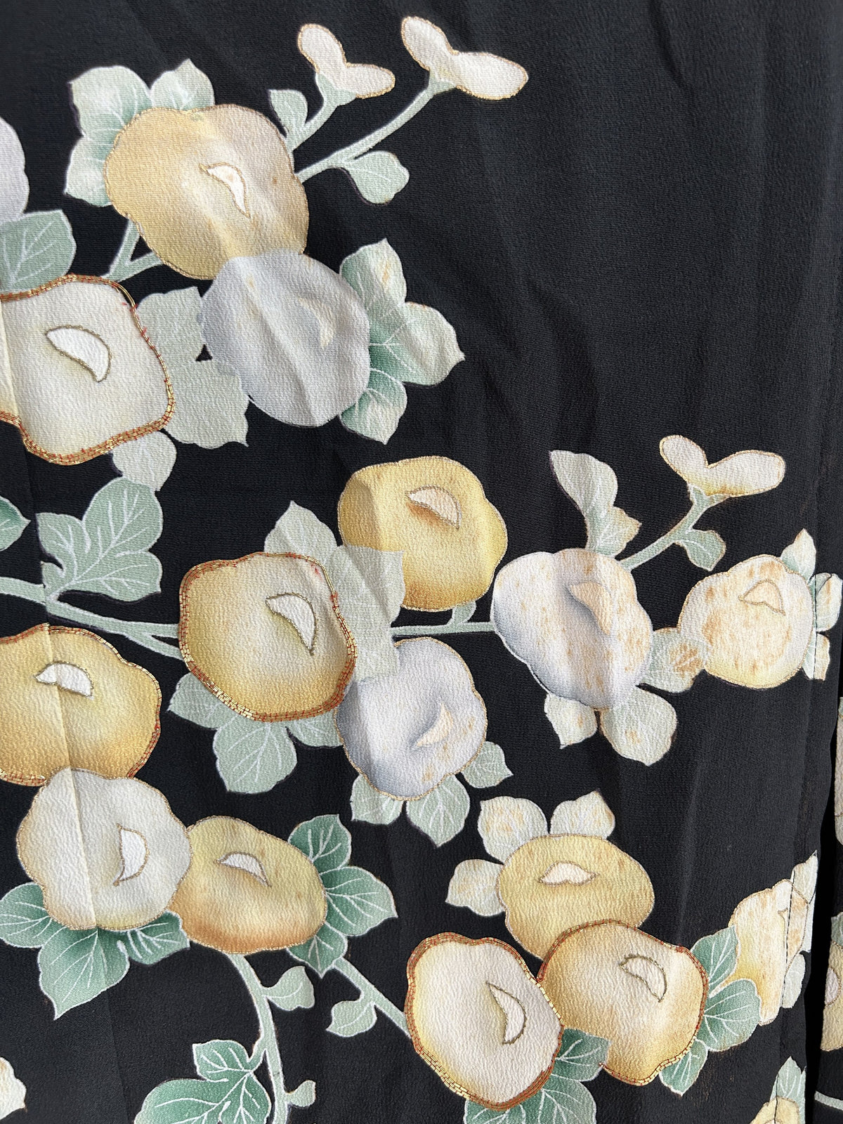Yellow and pale blue round blossoms with green leaves on black skirt