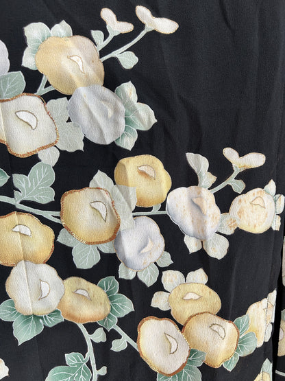 Yellow and pale blue round blossoms with green leaves on black skirt
