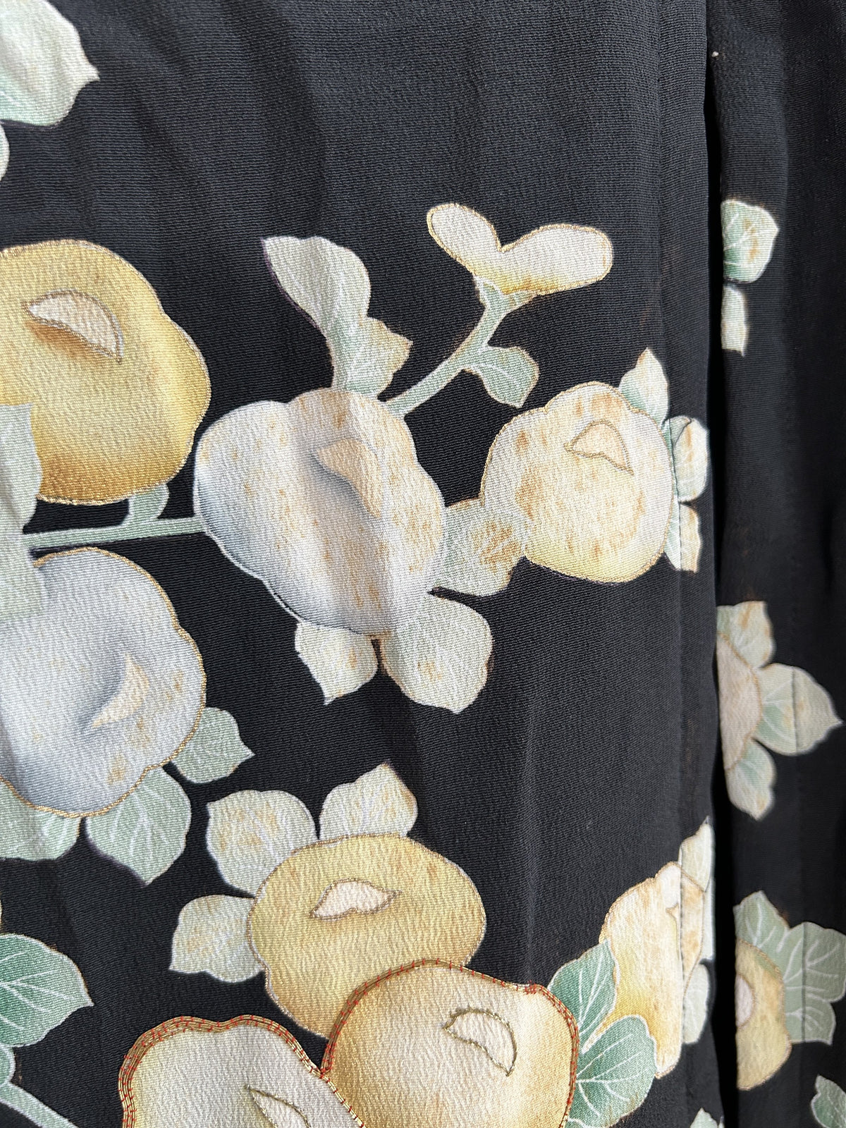 Round yellow and pale blue blossoms on black kimono skirt, close-up