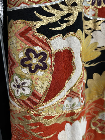 Red and gold shape with purple flowers on black kimono skirt, close-up
