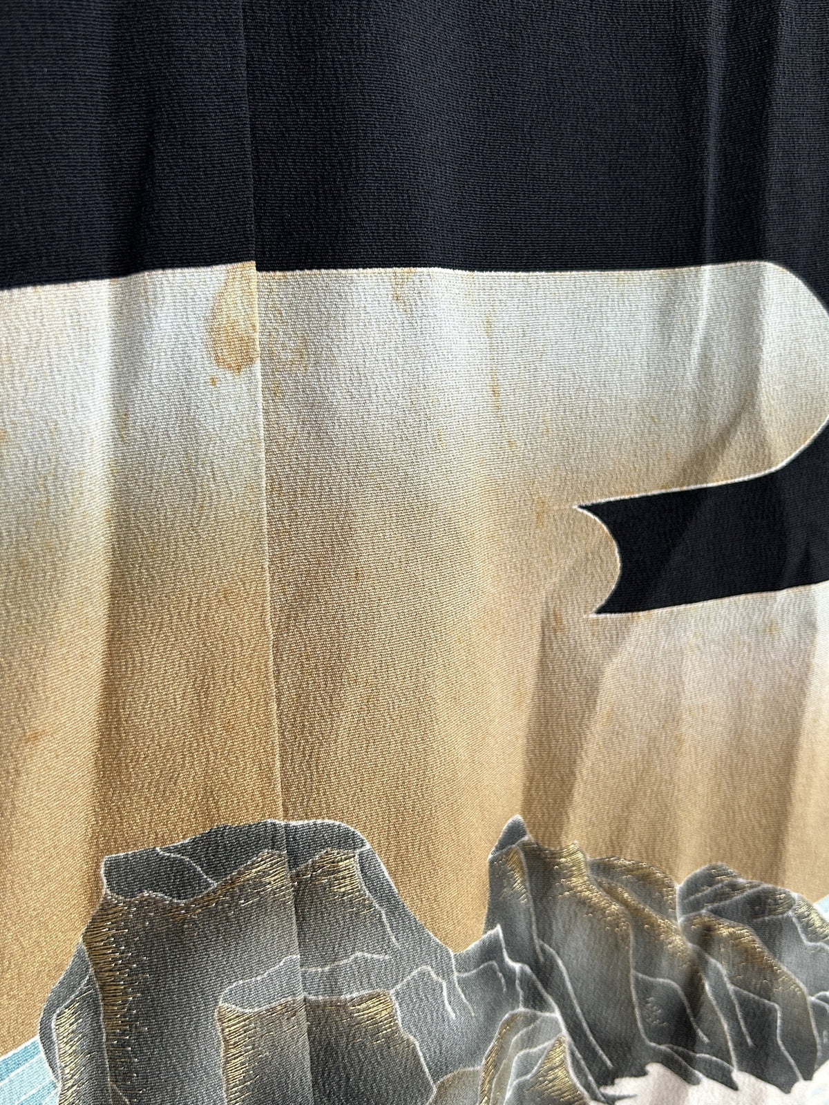 Beige and cream sky above grey rocks on black kimono skirt