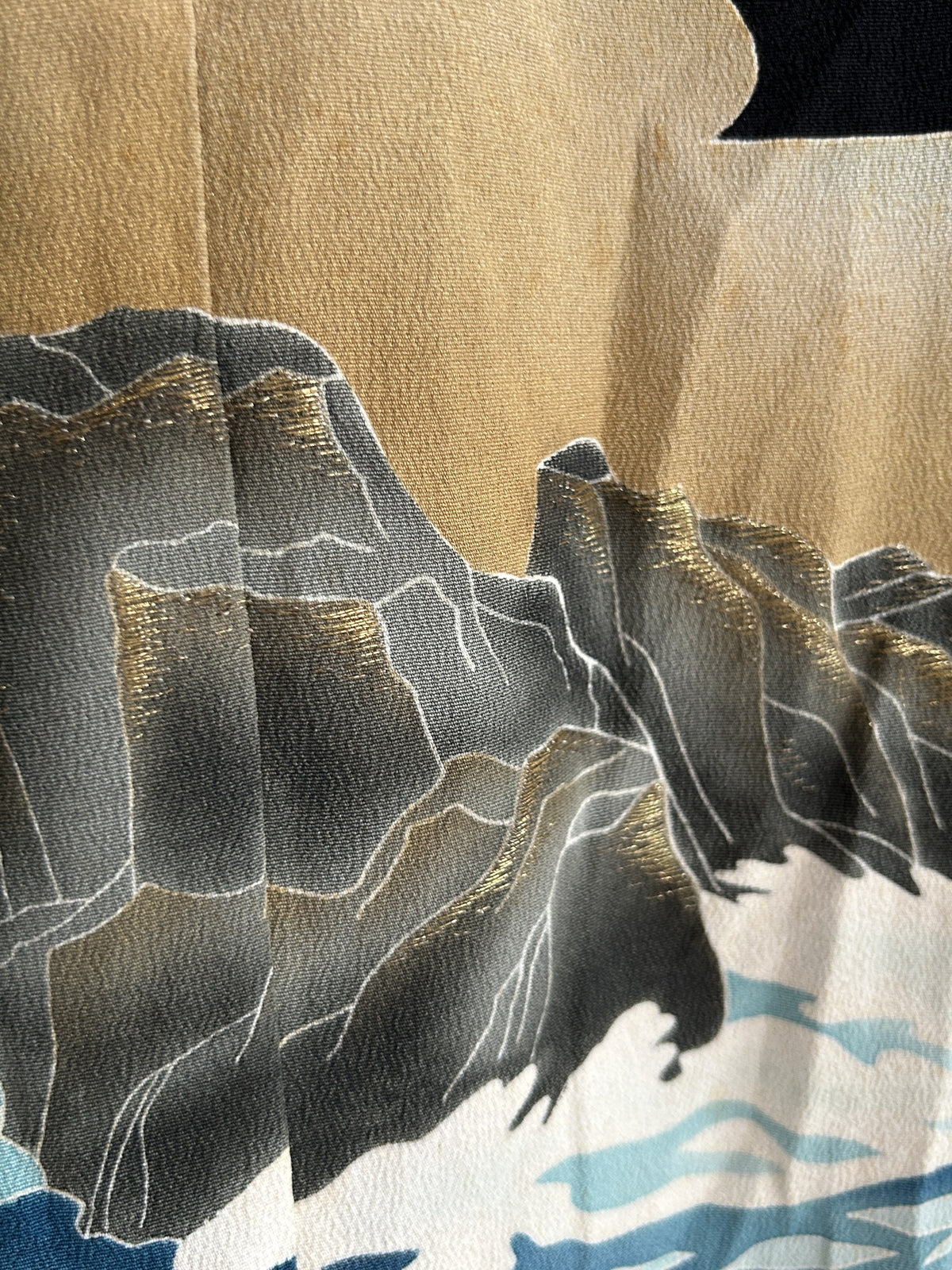 Grey rocks with gold highlights against beige sky, skirt detail