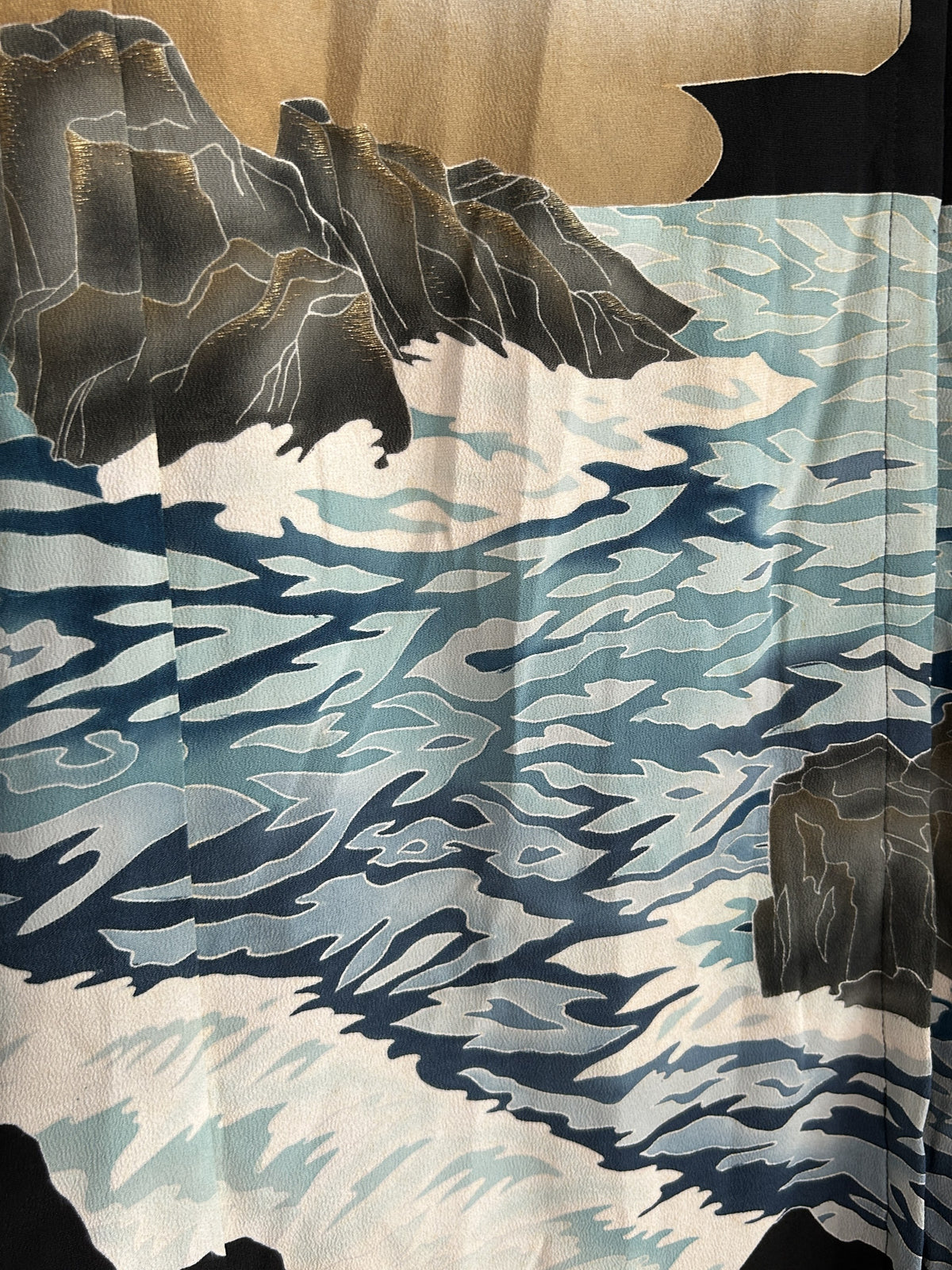 Blue and white waves with grey rocks on kimono skirt, close-up