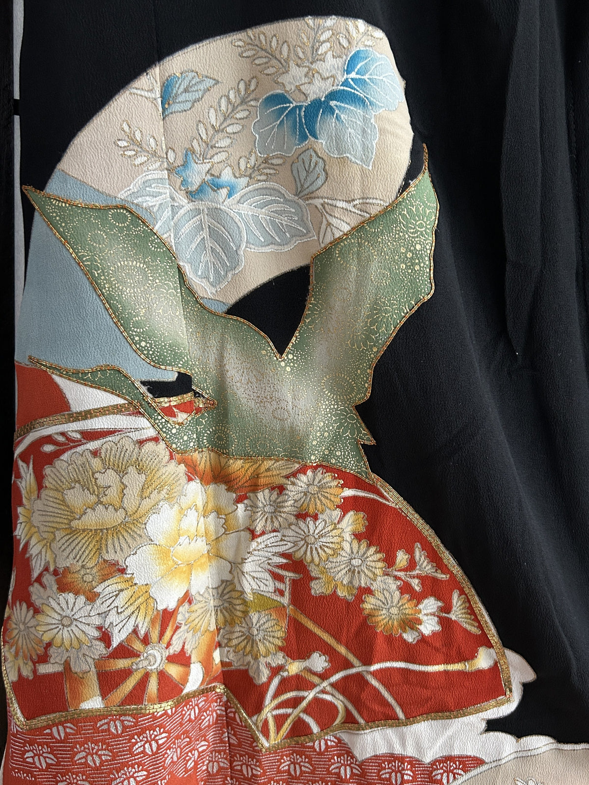 Green flying bird over red floral fan on black kimono skirt